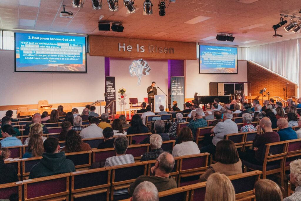 The congregation gathered for worship at Woodlands, beneath the words He Is Risen